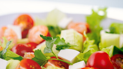 Salad in a Greek shrimp salad. A close-up salad of fresh vegetables, a plate of fresh salad with vegetables and herbs. The concept of a delicious and healthy dish. Greek salad with juicy tomatoes