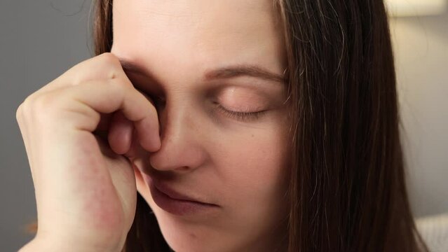 Closeup of brown haired female face feeling eye strain or migraine exhausted young woman bad weak blurry vision eyesight problem feeling sleepy