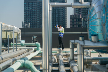 A professional engineer communicates via walkie-talkie on a building's rooftop, surrounded by...