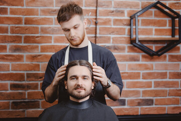 Barbershop hairdresser, brick background, warm toning. Portrait Man in barber chair