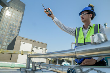 Construction supervisor raises radio to give instructions on a sunny day at an urban job site with...