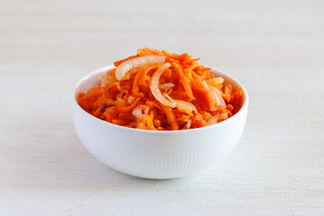 Fresh healthy vegetarian carrot salad with apple, onion and spices in the bowl. Side view, close up