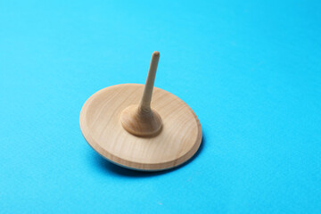 One wooden spinning top on light blue background, closeup. Space for text