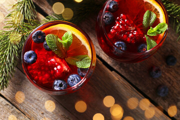 Aromatic Christmas Sangria drink in glasses and fir branches on wooden table, flat lay