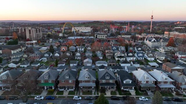 Hershey, Pennsylvania, Chocolate town establishing shot. Aerial truck shot of houses in an American neighborhood and Hershey Park in the background during autumn sunset.