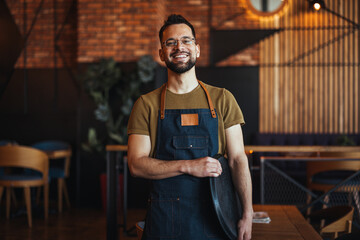 Friendly confident male owner at his cafe. Portrait of happy waiter in a cafe looking at camera. Copy space. Profesional Waiter in Restaurant - 789034537