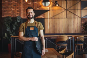 Rucksack Waist up portrait of handsome waiter smiling cheerfully at camera standing in restaurant or cafe, copy space. Young waiter serving coffee in a cafe and looking at camera. © Dragana Gordic