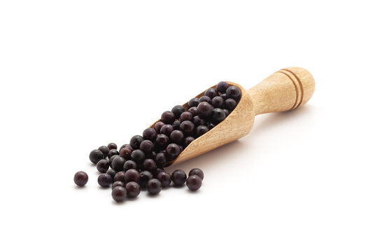 Front view of a wooden scoop filled with Fresh Organic Black nightshade or Makoy (Solanum nigrum) fruit. Isolated on a white background.