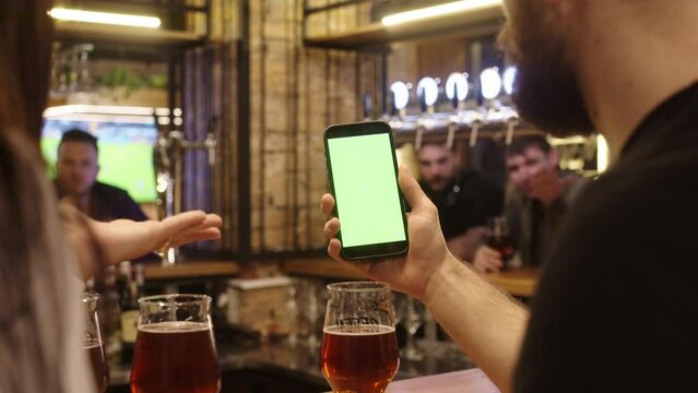 A young man uses a mobile phone with a white screen, placing bets on a football match online. Sports fan, bookmaker ratings. Layout.