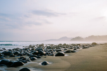 Morning tranquility captured in a serene coastal image, featuring small waves, rocky beach, and the...