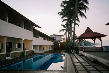 Tranquil coastal living awaits in this villa with a pool and coconut trees, an epitome of tropical paradise.