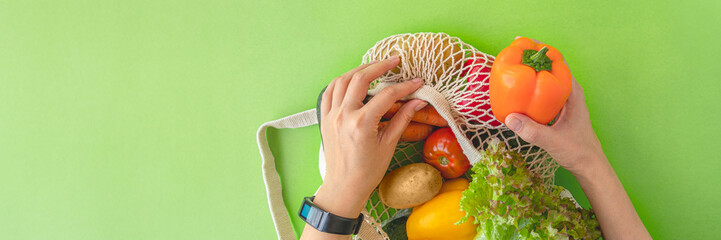 banner of top view of a woman's hands taking vegetables out of an eco-bag. tomatoes, cucumbers, bell peppers and lettuce in a reusable bag. The concept of recycling, respect for nature. flat lay, copy