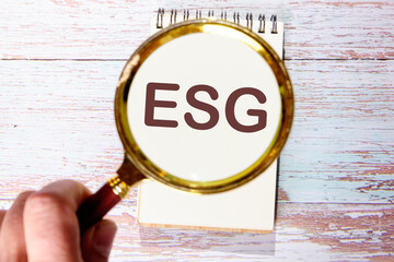 Business concept. Future environmental conservation and sustainable ESG modernization. Words ESG through a magnifying glass in a notebook against the background of old boards