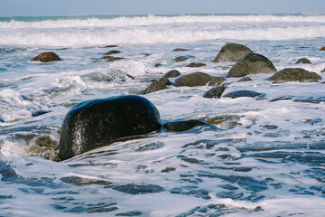 Morning tranquility captured in a serene coastal image, featuring small waves, rocky beach, and the calming aura of dawn