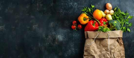 Vegetables and fruits in a paper bag placed on a dark background with space for text, top view. Concept of bagged food.