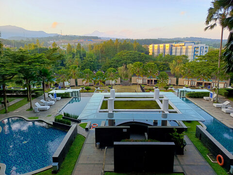 Tranquil hotel pool embraced by morning hills and verdant trees under a sunny sky, inviting guests to unwind and enjoy.