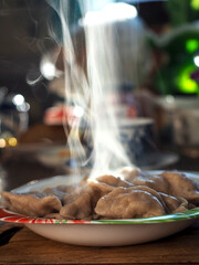 a plate of mouth-watering hot dumplings, steam rises above the plate