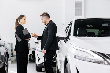 A car dealership manager or saleswoman advises a client or buyer. Showing a modern service for...