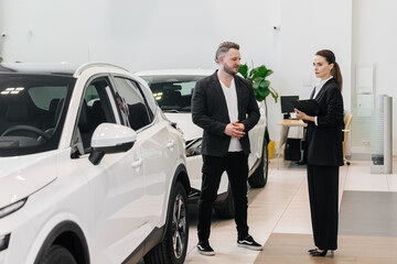 A car dealership manager or saleswoman advises a client or buyer. Showing a modern service for...