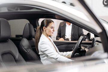 A male manager helps a businesswoman choose a new modern electric car. The concept of advertising modern cars, as well as buying and selling.