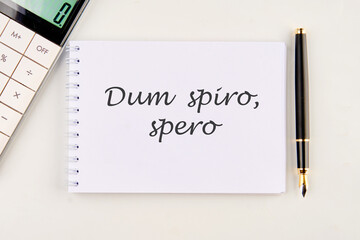 Dum Spiro Spero - latin phrase means While I Breath, I Hope. on a white notebook