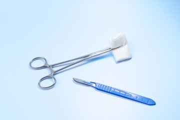 A pair of scissors and a pair of surgical scissors are on a blue surface