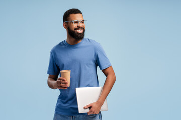 Portrait of young African American man in eyeglasses posing with coffee while holding laptop