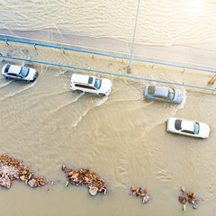 cars moving along a country road flooded from floods and floods, photographed from a drone and a...