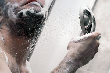 Man takes a shower. Shot of a young man taking a shower in the modern tiled bathroom.