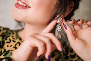 a girl with a manicure holding a long earring near her ear