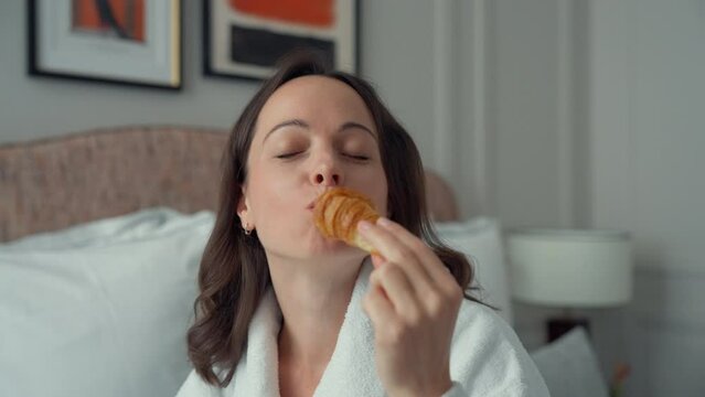 Woman Eating Pastry in Hotel Room