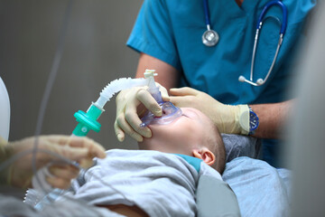 An anesthesiologist holds a breathing mask over the face of a young boy. Introduction to General...