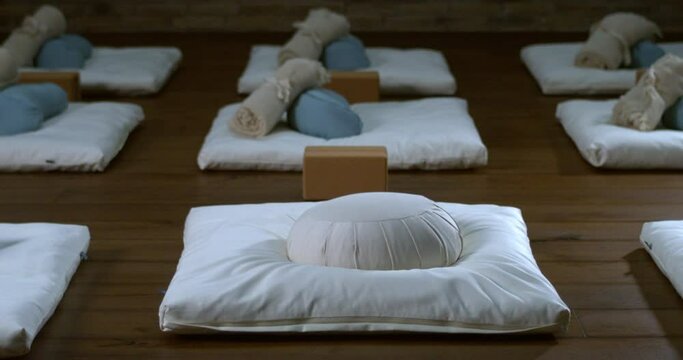 Super slow motion close up of meditation cushion is falling on soft pillow at quiet interior room of yoga center at 1000 fps. Enlightenment, mindfulness, inner peace concept.