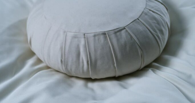 Super slow motion macro of meditation cushion is falling on soft pillow at quiet interior room of yoga center at 1000 fps. Enlightenment, mindfulness, inner peace concept.