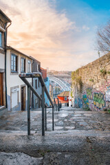 Street view of the narrow cobblestone streets of Porto with its old buildings and the Dom Luís I Bridge. Fragment of a metal railroad bridge, Portugal. - 789096319