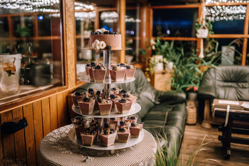 Valmiera, Latvia- July 28, 2023 - A dessert stand with a cake and various sweets in an indoor setting with string lights and cozy decor.