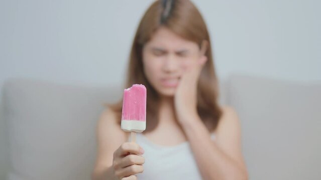 Teeth Sensitive to Cold concept. woman hold Ice cream and having toothache and pain after eat. Tooth Decay or Gum Disease, Grinding Teeth and Stress, Exposed Nerve Roots, Crack and Receding Gums