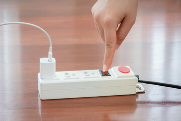 Close-up of electrician's hand using red push button to turn on the power strip,Save electricity by...