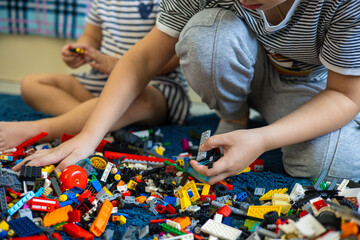 Children assemble a construction set on the floor in the children's room. Children play in the room with a construction set, assembling various toys from it. Children play with a construction set.