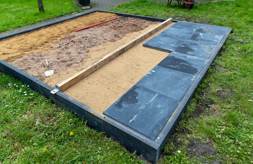 Sand als Unterbau gerade abziehen um Gehwegplatten darauf zu verlegen.