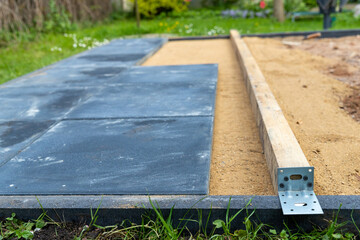 Sand als Unterbau gerade abziehen um Gehwegplatten darauf zu verlegen.