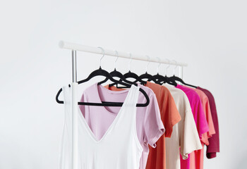 row of t-shirts on a hanger against a background of a white wall hanger - 789113505