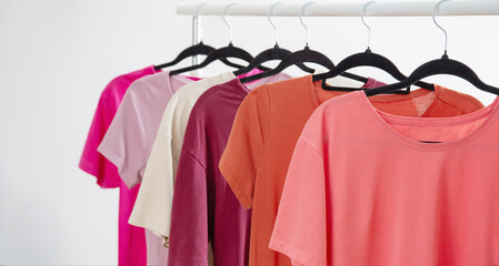 row of t-shirts on a hanger against a background of a white wall hanger - 789113522