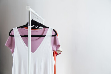 row of t-shirts on a hanger against a background of a white wall hanger - 789113568