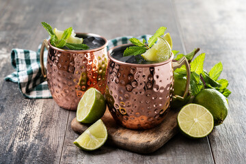 Moscow mule cocktail served with ice and lime slice on wooden table