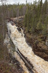 Log floating flume at Auttiköngäs waterfall in cloudy spring weather, Rovaniemi, Lapland, Finland.