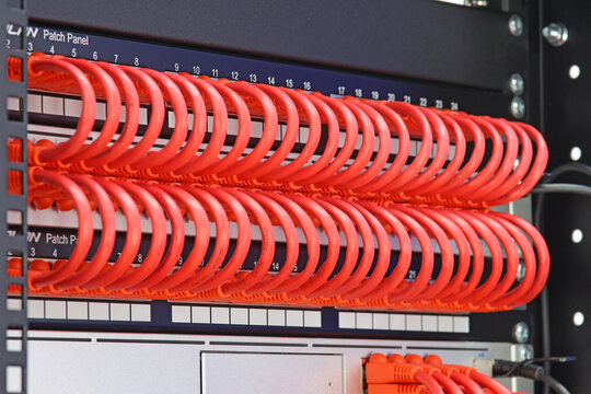 An Ethernet Internet signal switch with patch cords connected to patch panels in a telecommunications rack. Soft focus.