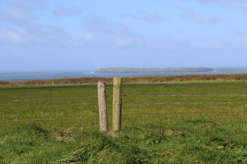 A view across farmland to the coast and Stokholm Island near Marloes in Pembrokeshire, Wales, UK.