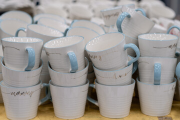 A stack of white mugs and plates in the store for sale. White and clean dishes.