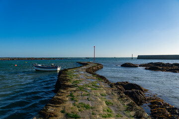 Fototapeta na wymiar Une barque solitaire amarrée au pied de la jetée, témoignant du calme qui règne à Penmarc'h, Finistère.